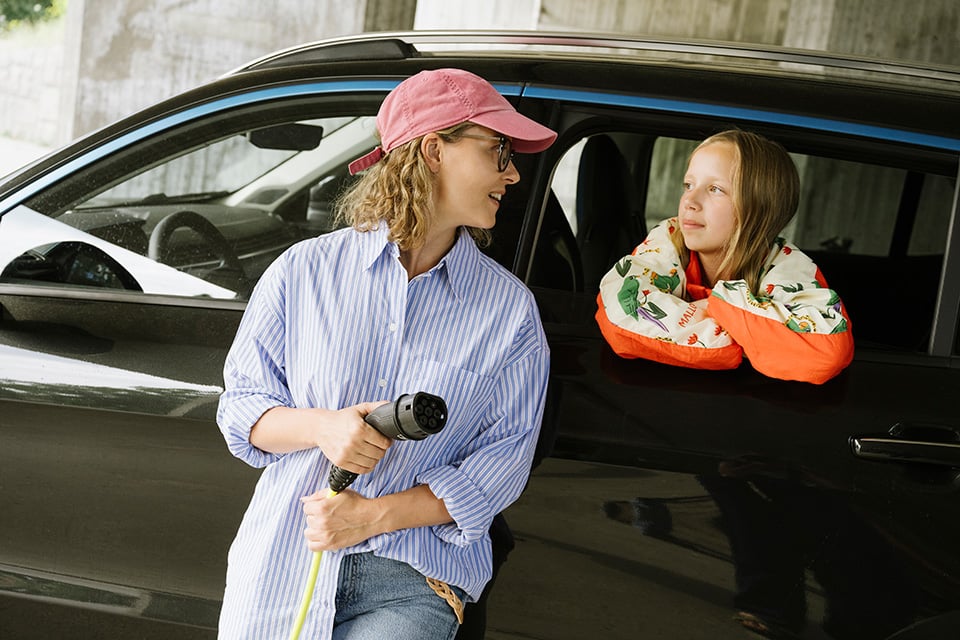 En kvinna och ett barn som laddar en elbil