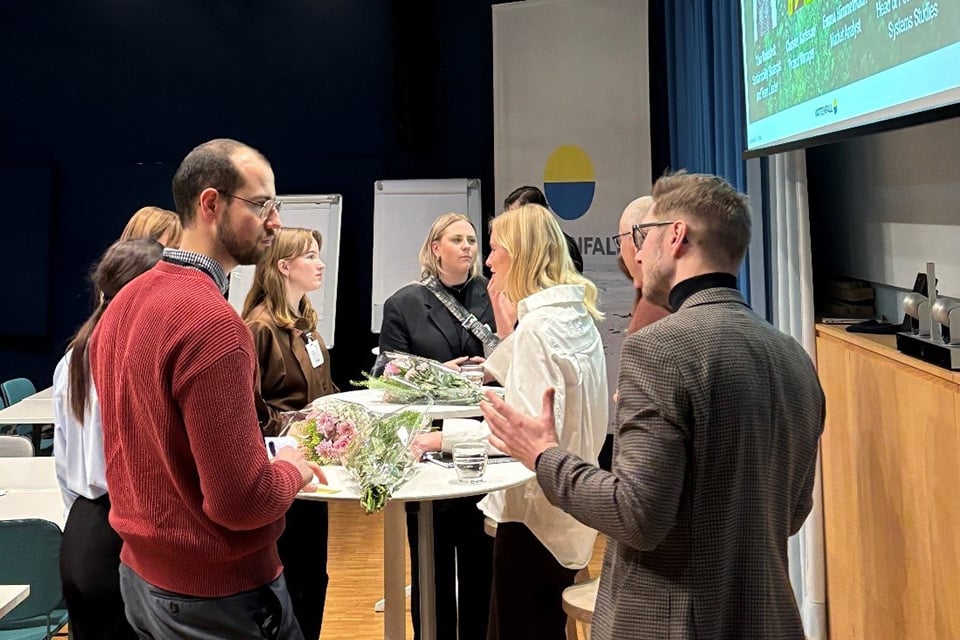 Traineer och paneldeltagare står vid runda bord och pratar med varandra.