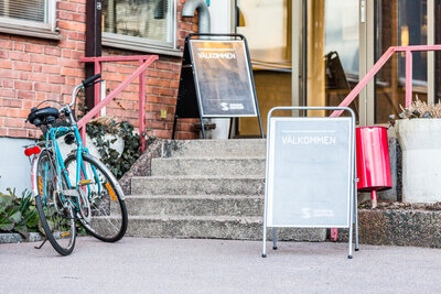 Skylt med välkommen och cyklar som står utanför en lokal.