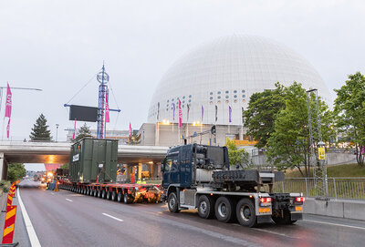 Ett långt släp och flera lastbilar ska ta sig fram under en vägbro vid Globen